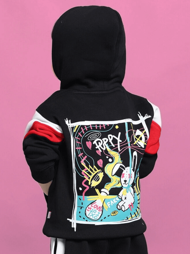 Child wearing black beanie hoodie with colorful graphic design on pink background.