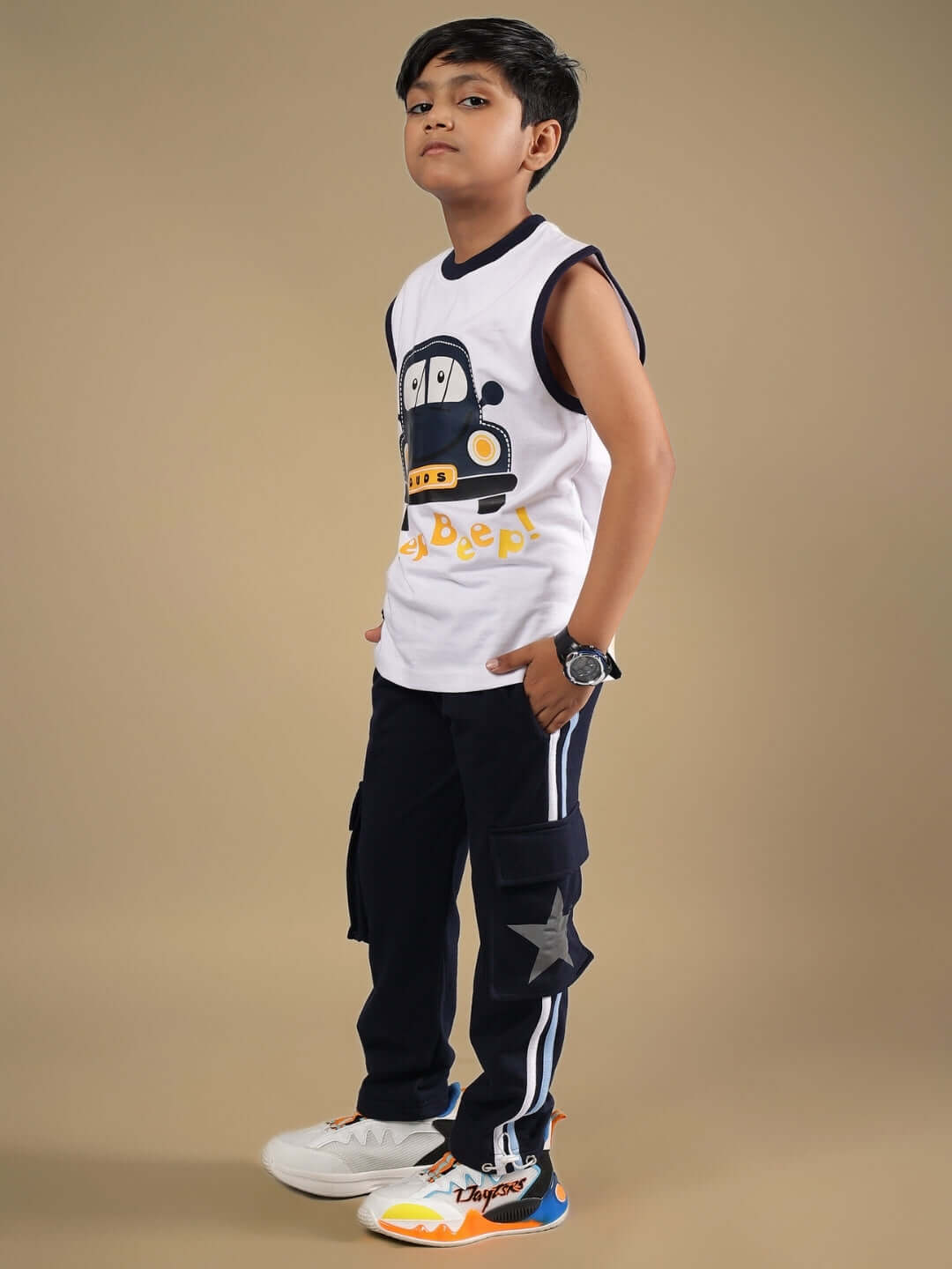 Child wearing BEEP BEEP CO-ORD FOR BOYS & GIRLS WHITE NAVY outfit with cartoon car design, standing confidently against a light brown backdrop.