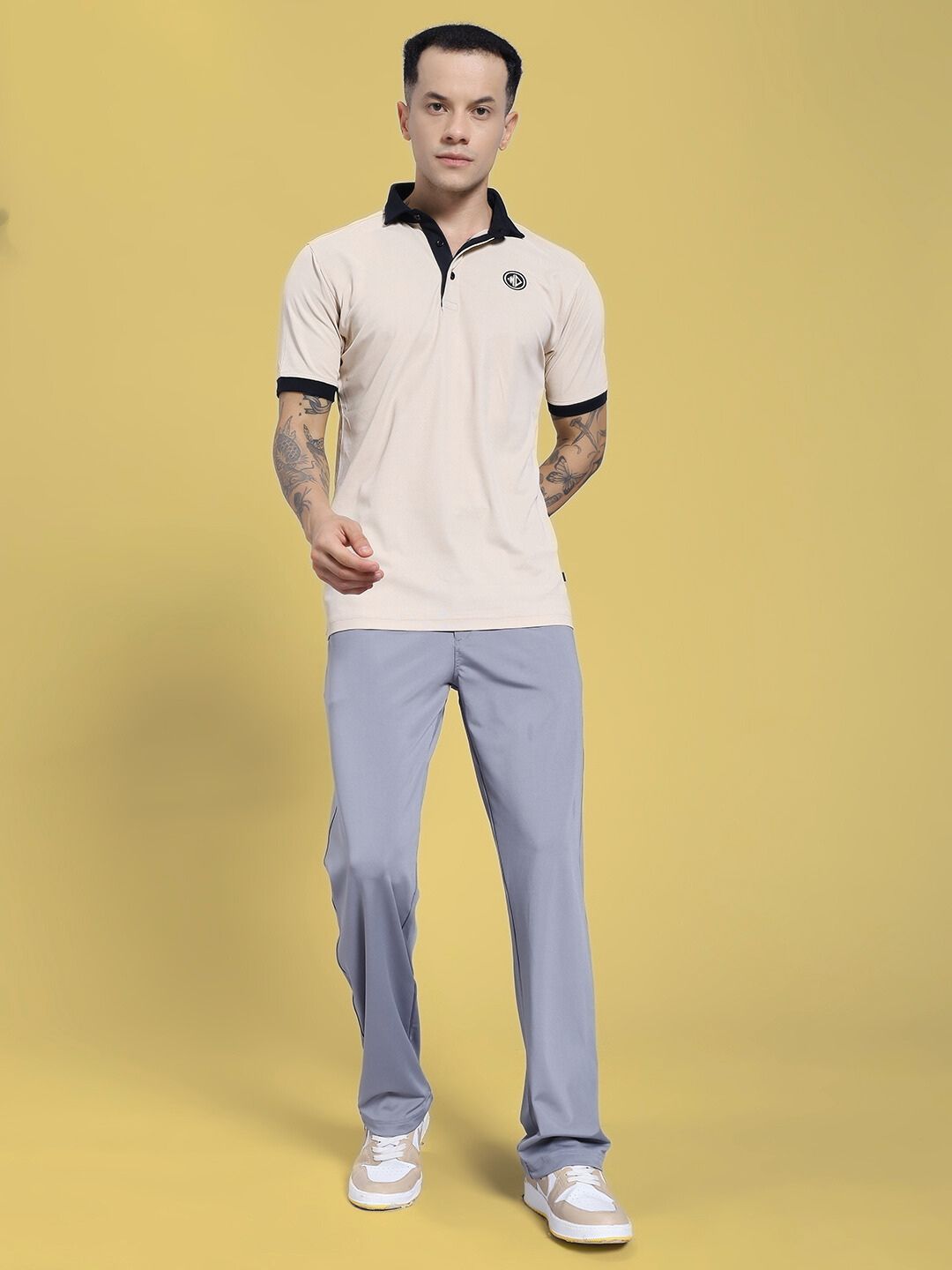 Model wearing REVOXX RELAXED FIT JOGGER GREY with a beige polo shirt, standing against a yellow background.