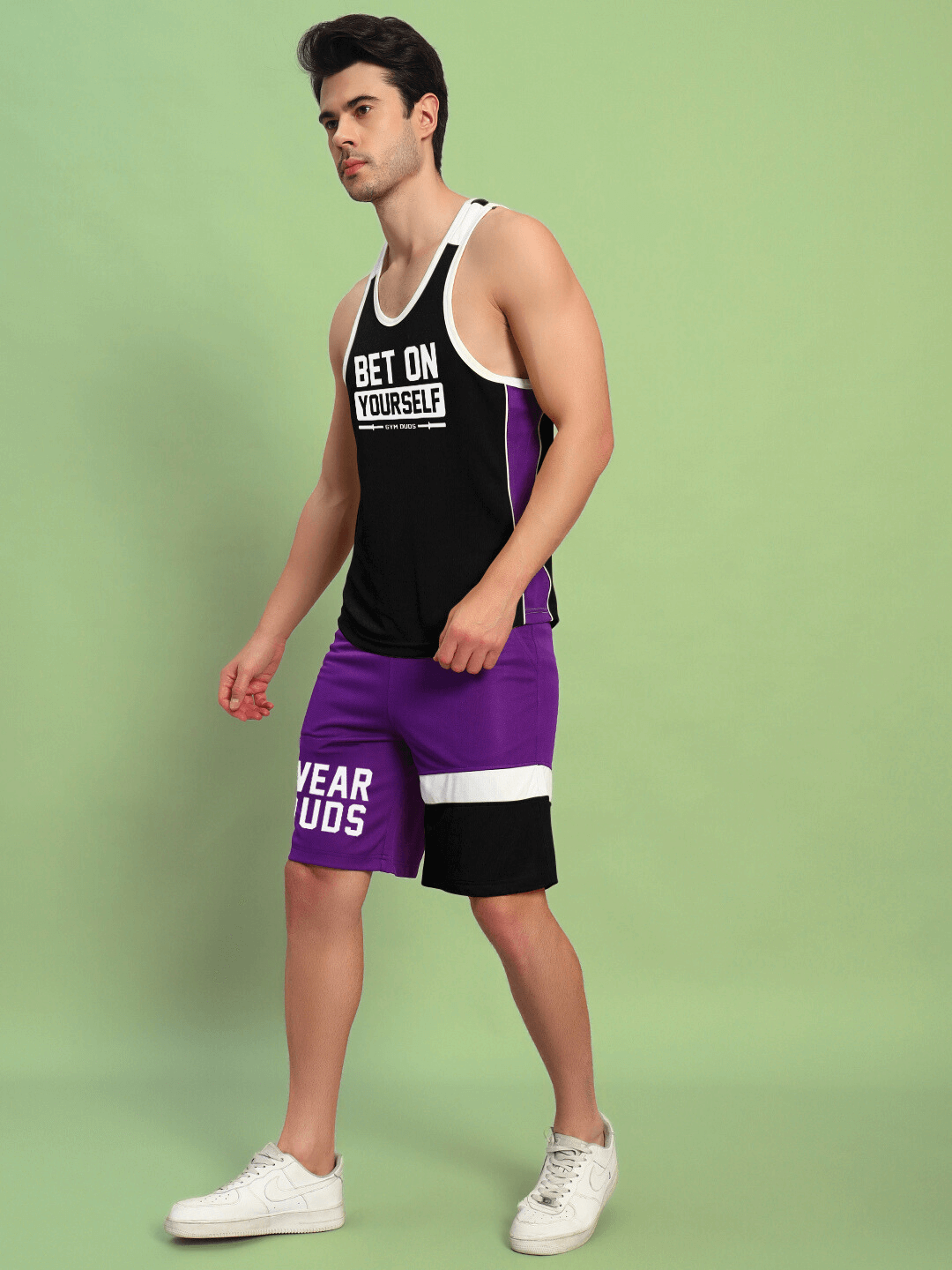 Man wearing BET ON YOURSELF GYM CO-ORD SET BLACK PURPLE, sporty black top and purple shorts, sports polyester fabric.
