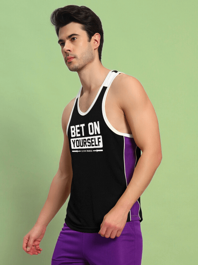 Man wearing BET ON YOURSELF GYM T-SHIRT BLACK with purple shorts, customizable fit options available.