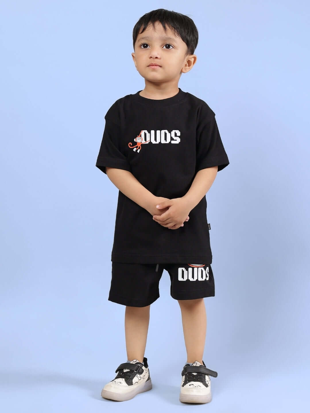Young child wearing BINGO CO-ORD FOR BOYS & GIRLS BLACK set, featuring a black top and shorts, made by DUDS, shown against a blue background.