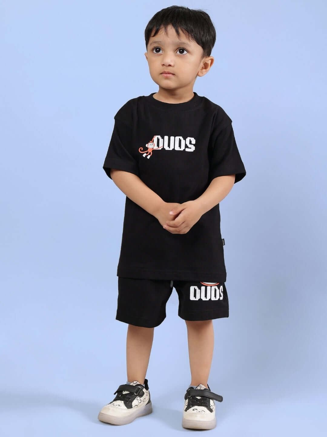 Child wearing a black t-shirt and BINGO SHORTS FOR BOYS & GIRLS BLACK, standing against a blue background.