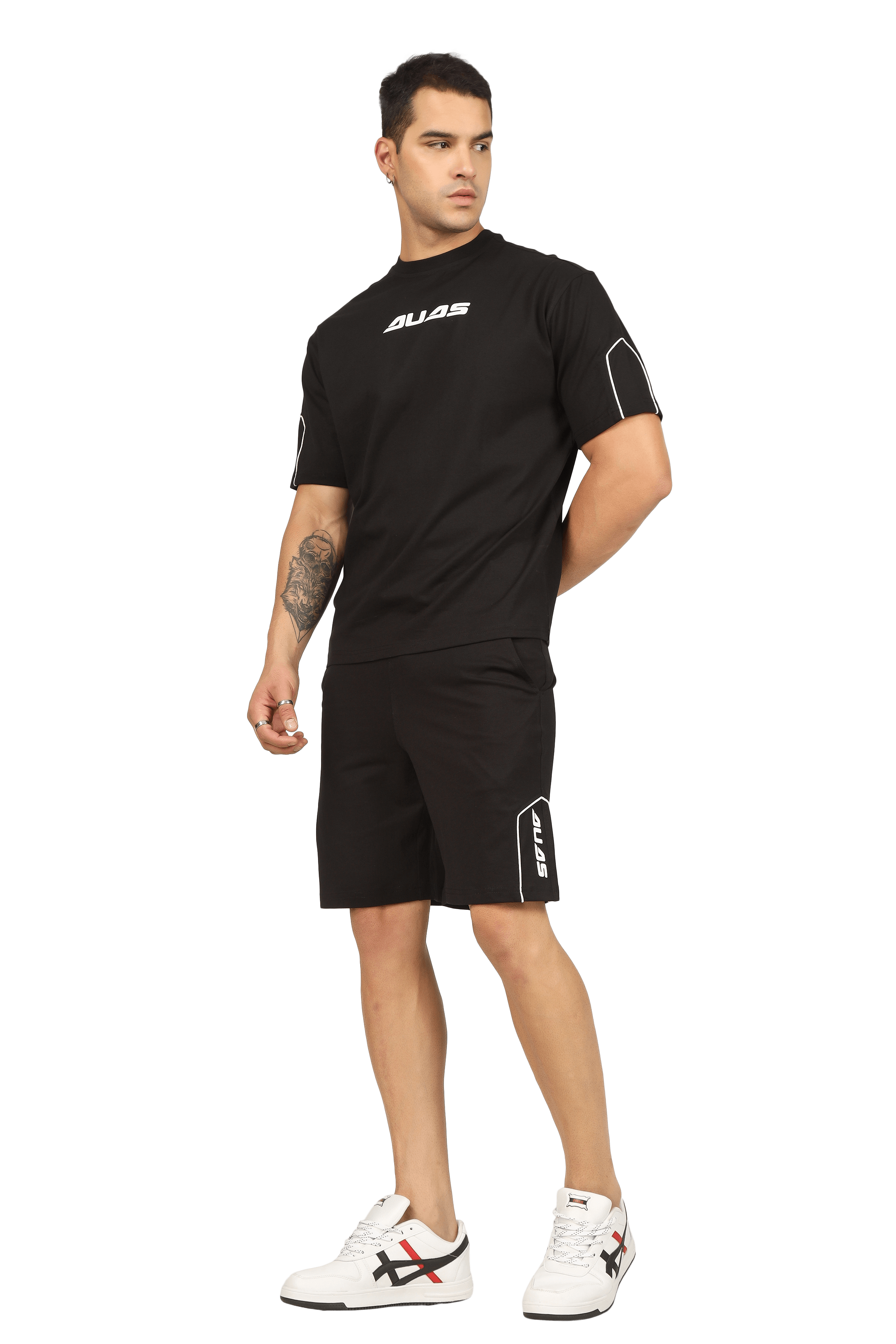 Man wearing a stylish minimal shaped cord co-ord set with a black t-shirt and shorts, standing confidently in white sneakers.