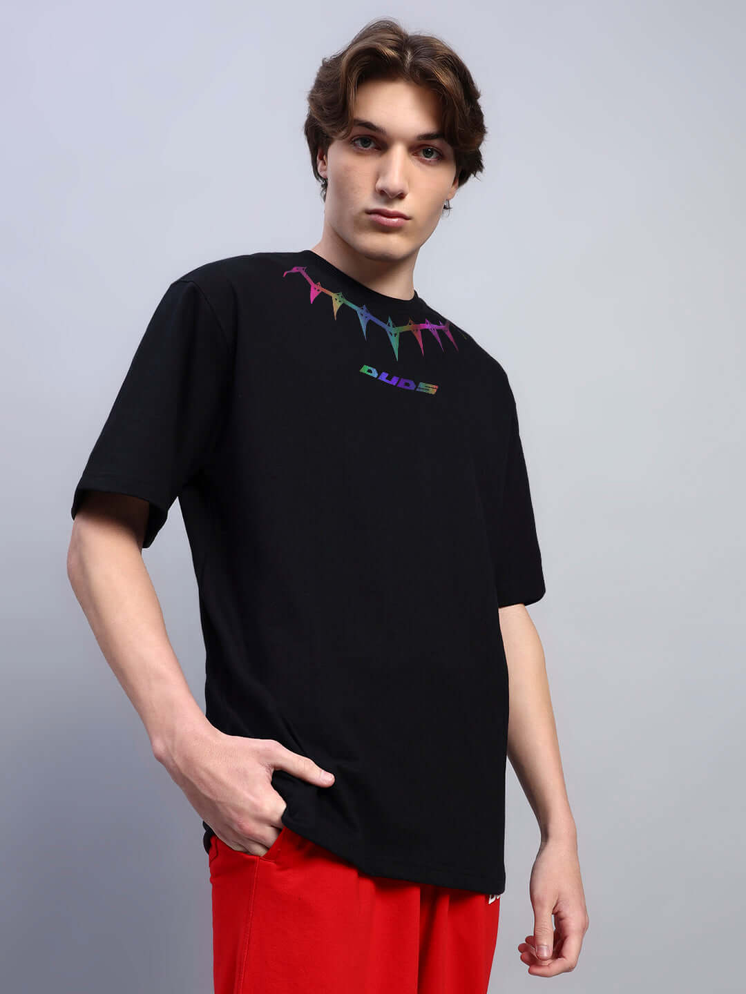 Model wearing black oversized T-shirt with colorful reflective pattern, made of premium heavy gauge fabric, by Color By Colours.