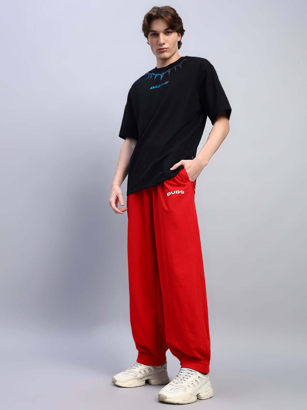 Model wearing oversized Black Panther t-shirt, black, made of premium cotton fabric, paired with red pants, showcasing casual style.