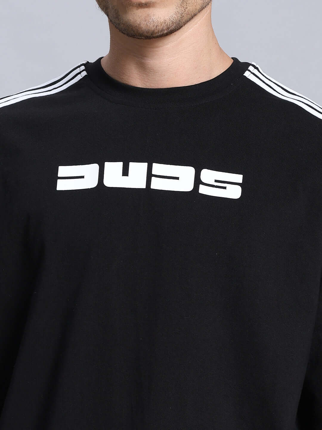 Close-up of a black sweatshirt with white text design on the front and striped detailing on shoulders.