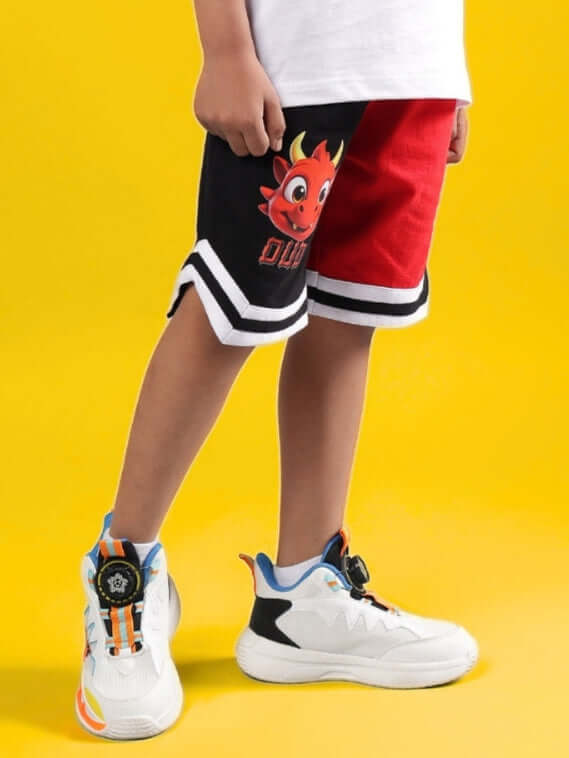 Child wearing CASSIE SHORTS FOR BOYS & GIRLS BLACK-RED with a playful design.