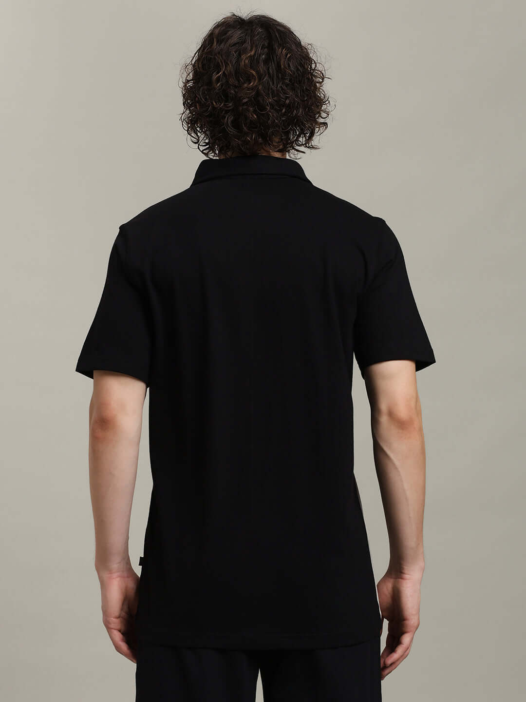 Back view of a person wearing a black short-sleeve polo shirt