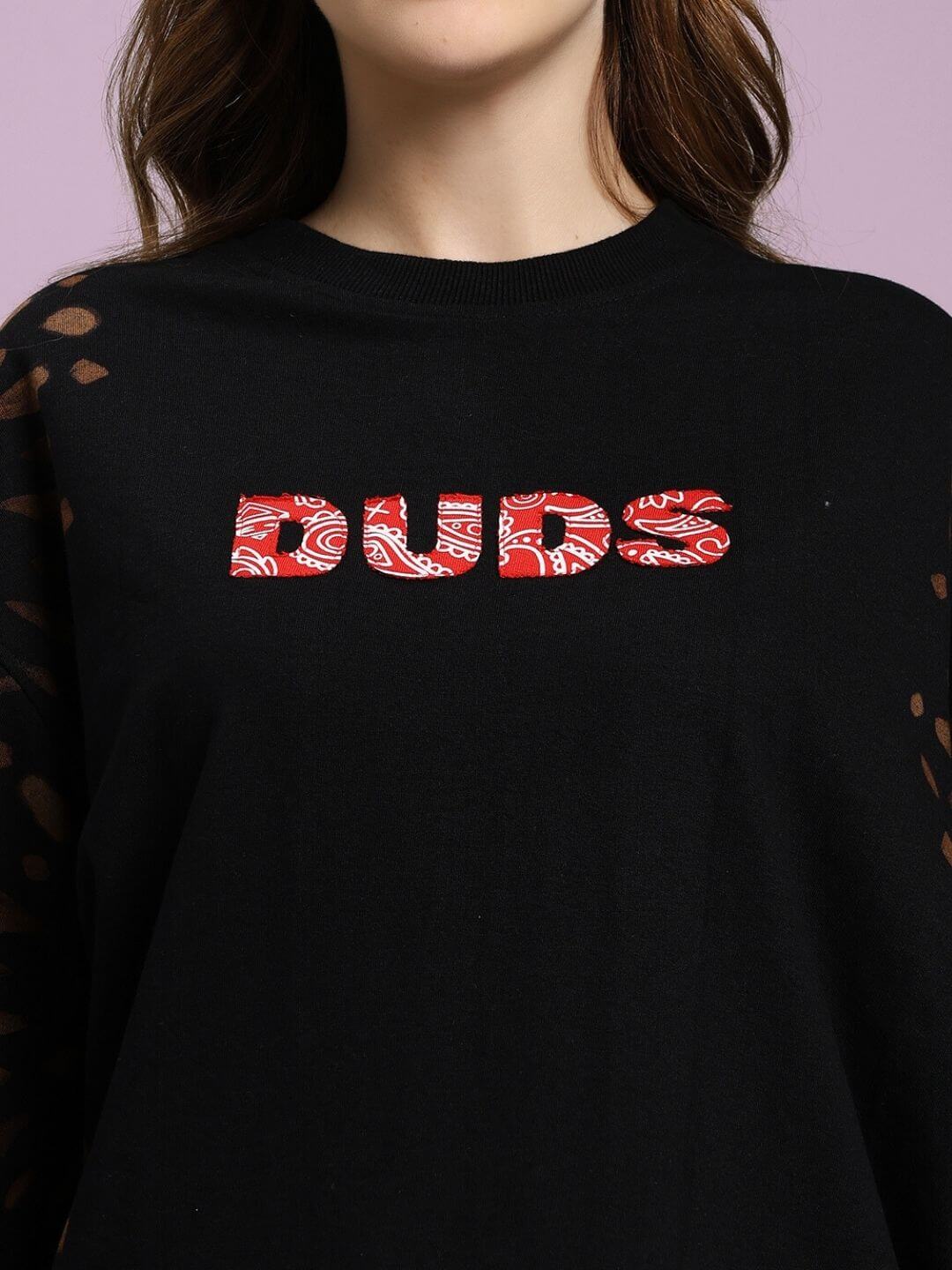 Woman wearing WOMEN'S SHADOW SWIRL TIE-DYE T-SHIRT BLACK with red 'DUDS' text.