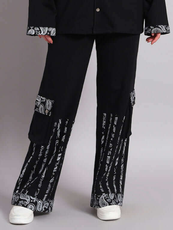 Person wearing black Sanganeri pants with intricate white patterns and white shoes.