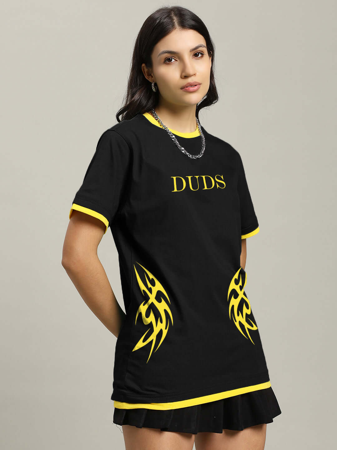 Woman wearing black t-shirt with yellow accents and tribal design, labeled 'DUDS'. Stylish casual wear for women.