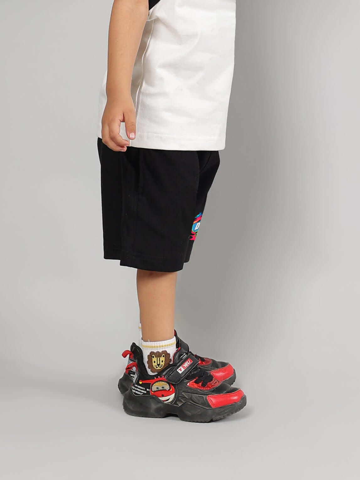Child wearing black Alien shorts for boys and girls, styled with red sneakers and a casual white top.