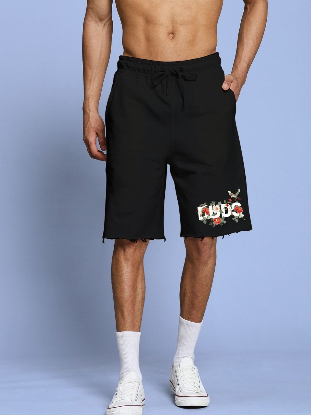Man wearing ROSE CHARM RELAXED FIT CO-ORD SET BLACK featuring floral design shorts, standing against a light blue background.