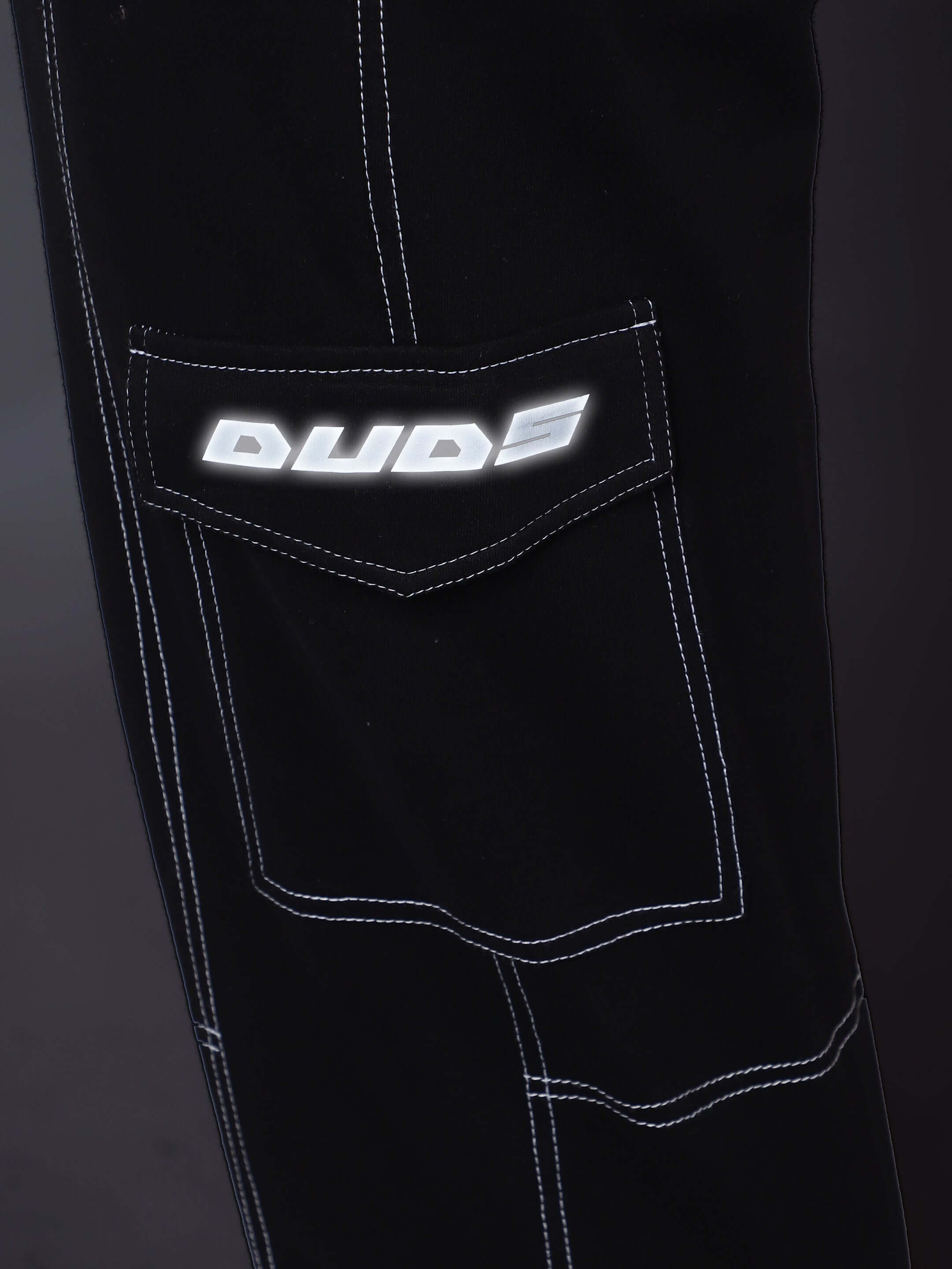Close-up of DUDS logo on black carpenter cargo pant with detailed white stitching.