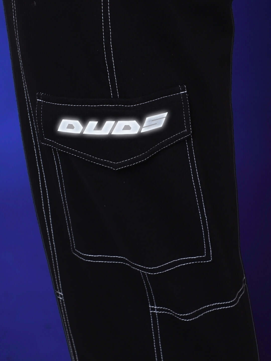 Close-up of black carpenter cargo pant with white stitching and embroidered "DUDS" logo, highlighting craftsmanship and style.