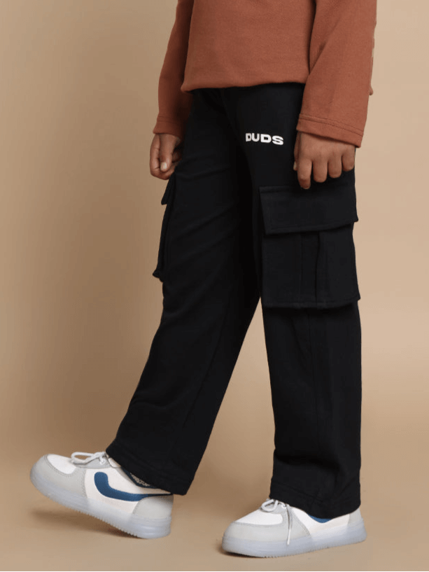Black jogger pants labeled 'DUDS' worn by a child, featuring cargo pockets for boys and girls, available for custom fit.