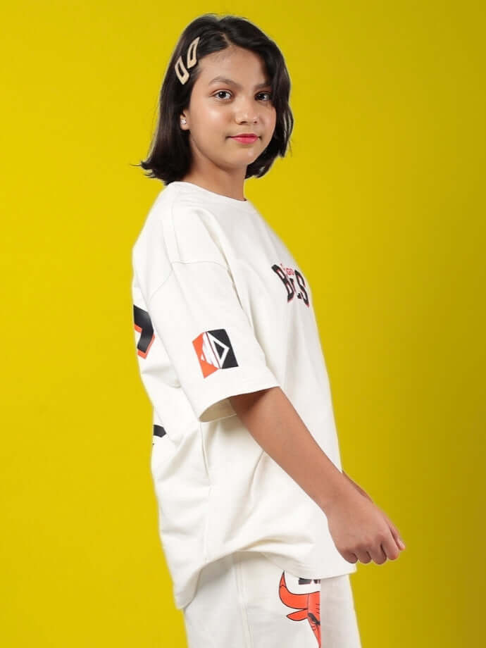 Girl wearing BLAZE BULLS OVERSIZED T-SHIRT FOR BOYS & GIRLS OFF WHITE with graphic design on yellow background