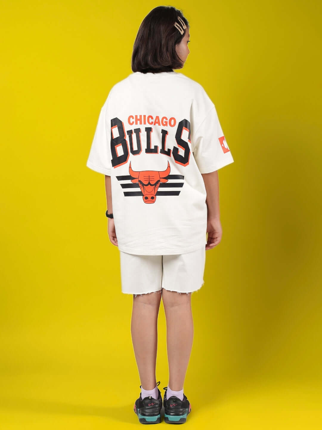 Back view of child wearing Blaze Bulls Co-ord for Boys & Girls Off White, featuring Chicago Bulls graphic tee and shorts on yellow background
