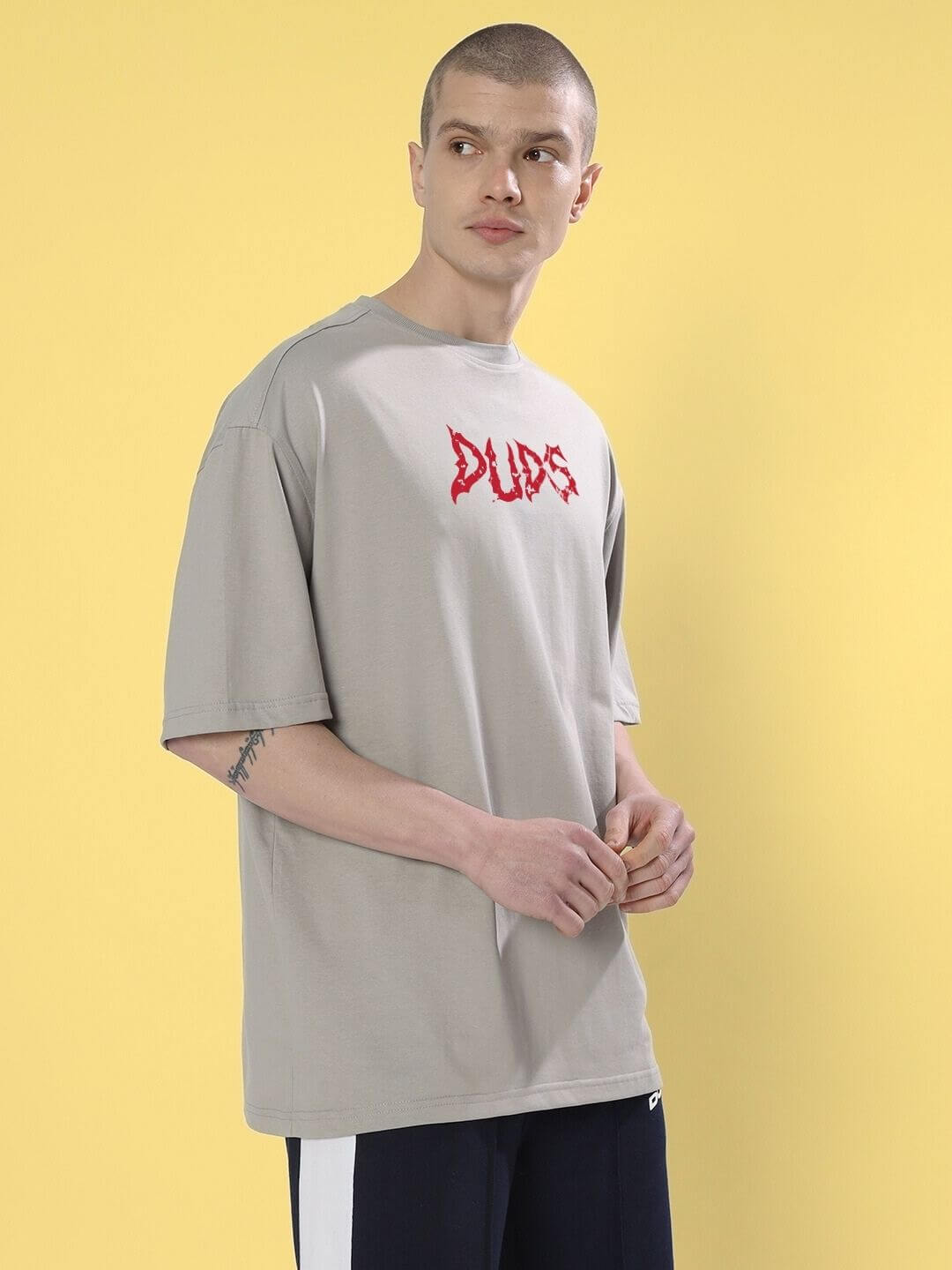 Model wearing BLOODY EYE OVER-SIZED T-SHIRT GREY with red graphic text, showcasing urban minimalism and street-ready style.