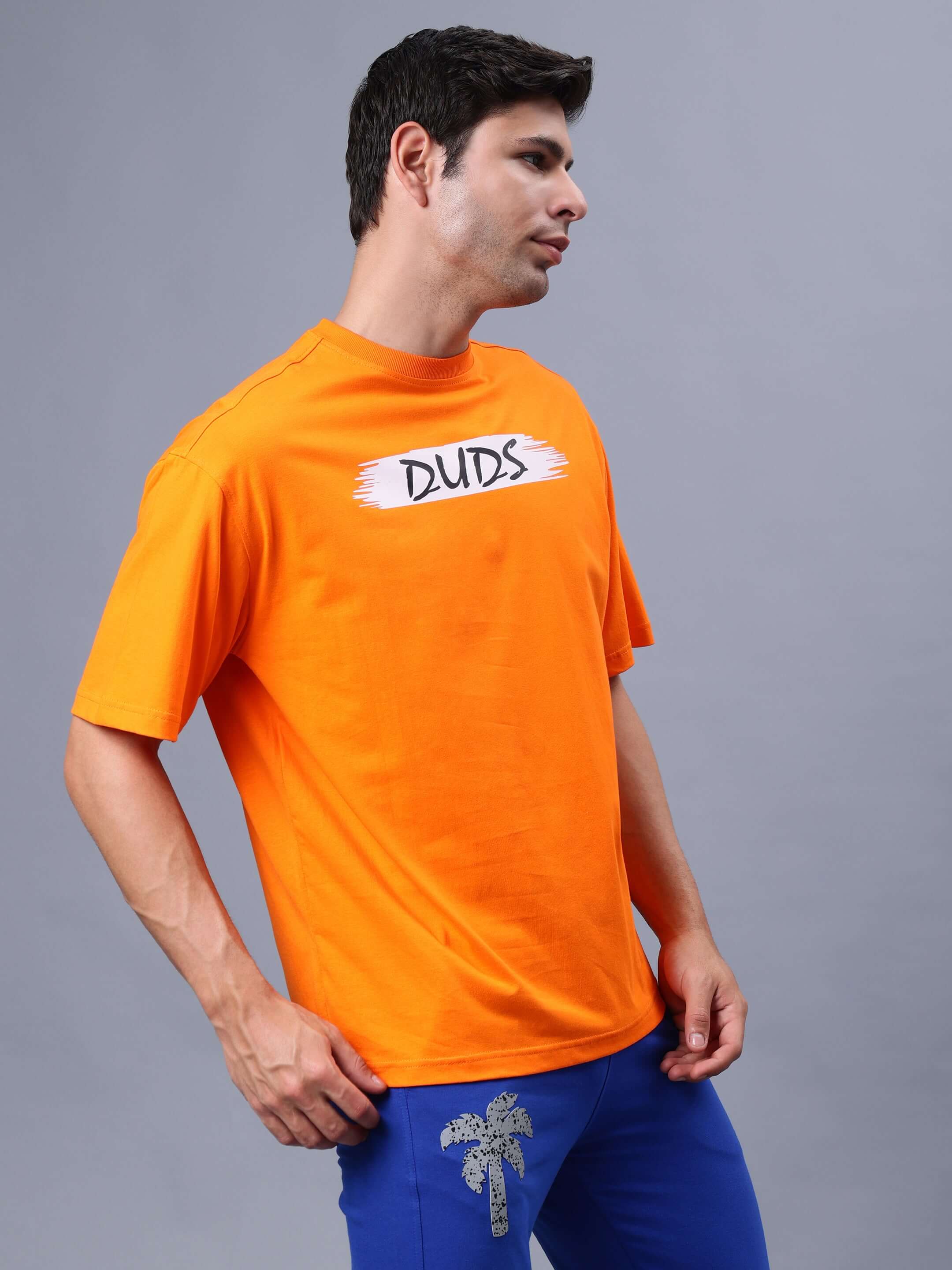 Man wearing orange oversized BLOOM Quote T-shirt from DUDS, featuring bold text and casual fit.
