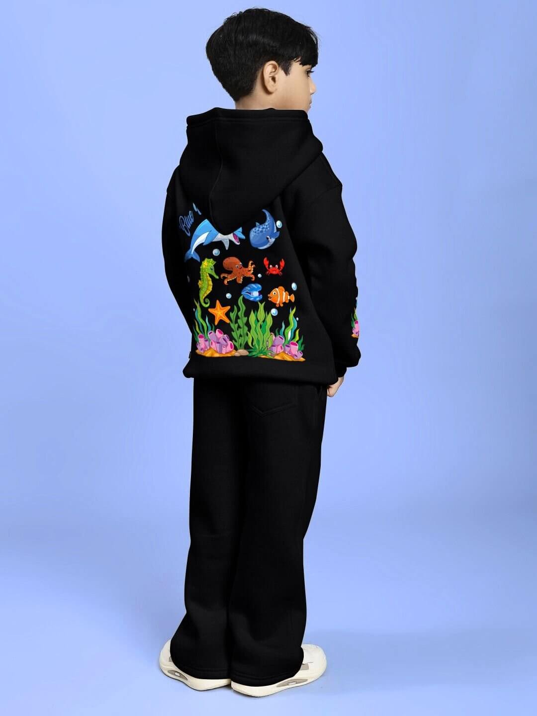 Child wearing BLUE OCEAN WORLD FLEECE CO-ORD FOR BOYS AND GIRLS BLACK with marine-themed design on the back.