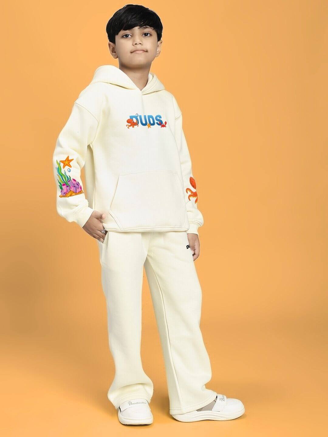 BLUE OCEAN WORLD FLEECE CO-ORD FOR BOYS AND GIRLS OFF-WHITE worn by a child standing on an orange background.