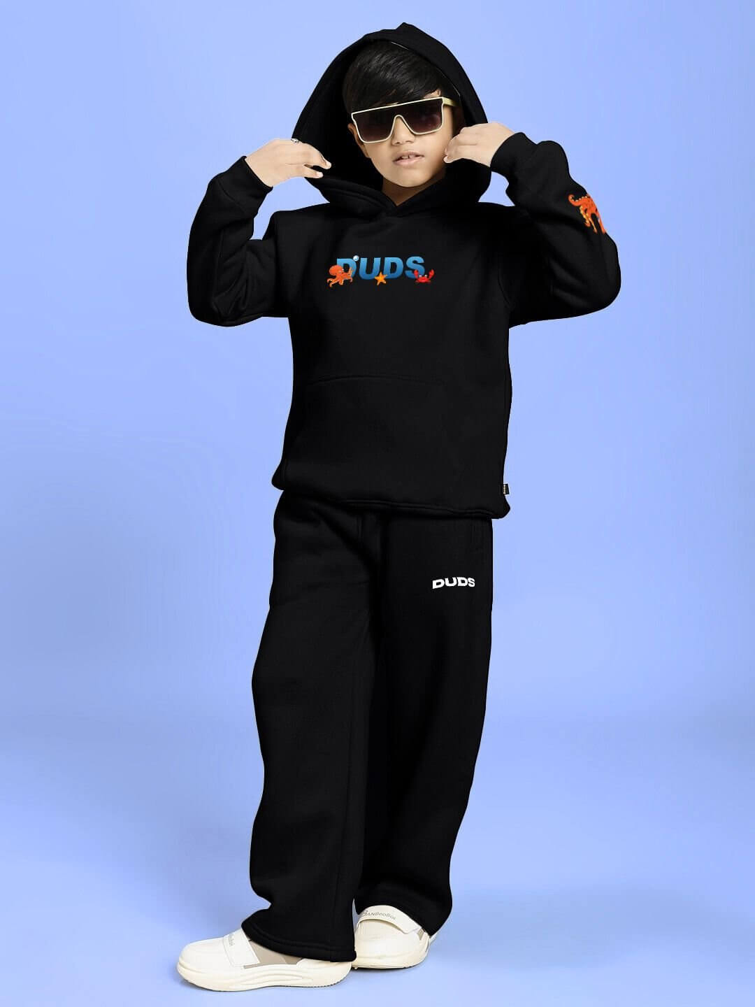Child wearing BLUE OCEAN WORLD FLEECE CO-ORD FOR BOYS AND GIRLS BLACK with sunglasses and white sneakers, standing confidently