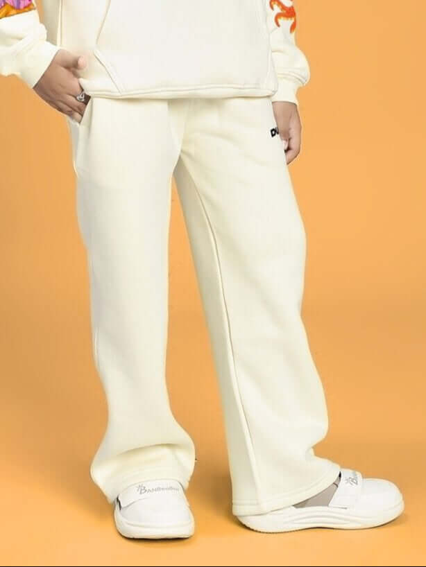 Child wearing BLUE OCEAN WORLD FLEECE JOGGER FOR BOYS AND GIRLS OFF-WHITE, standing against an orange background with matching shoes.