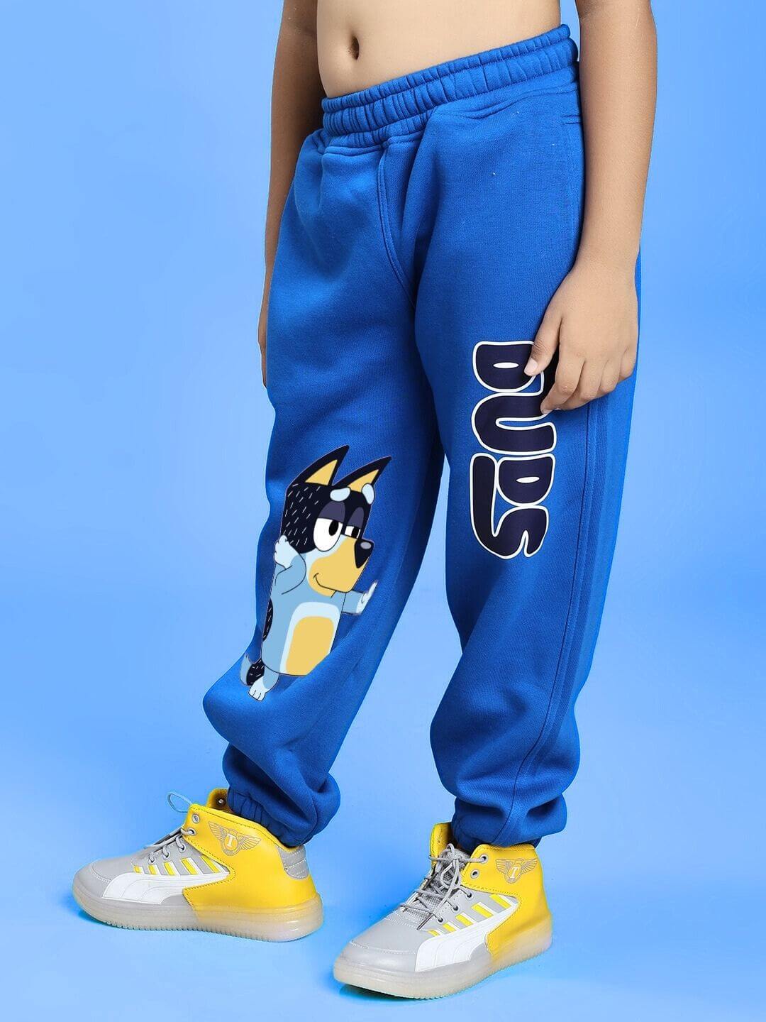 Child wearing BLUEY BINGO FLEECE CO-ORD FOR BOYS AND GIRLS WHITE BLUE with blue joggers featuring Bluey character and yellow sneakers.