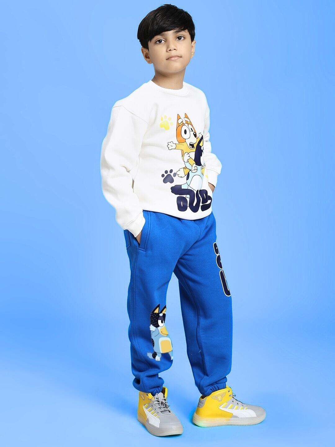 Boy wearing BLUEY BINGO FLEECE JOGGER FOR BOYS AND GIRLS BLUE standing against a blue background