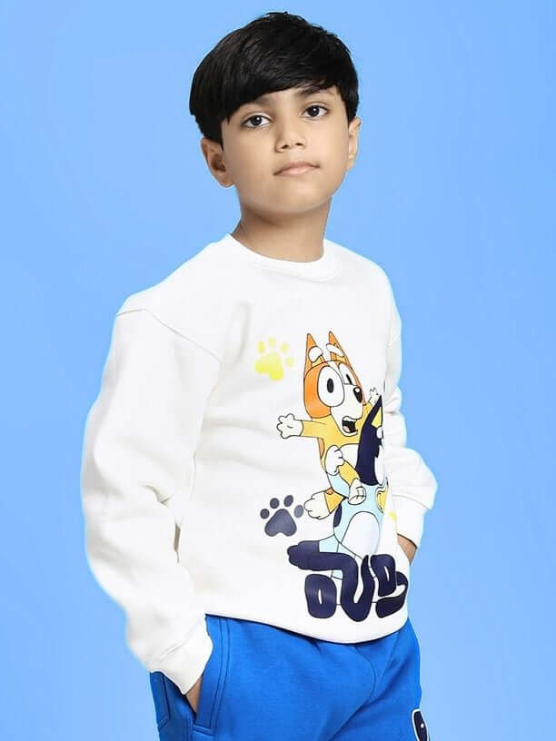 Child wearing BLUEY BINGO FLEECE SWEATSHIRT FOR BOYS AND GIRLS WHITE with character print, against blue background.