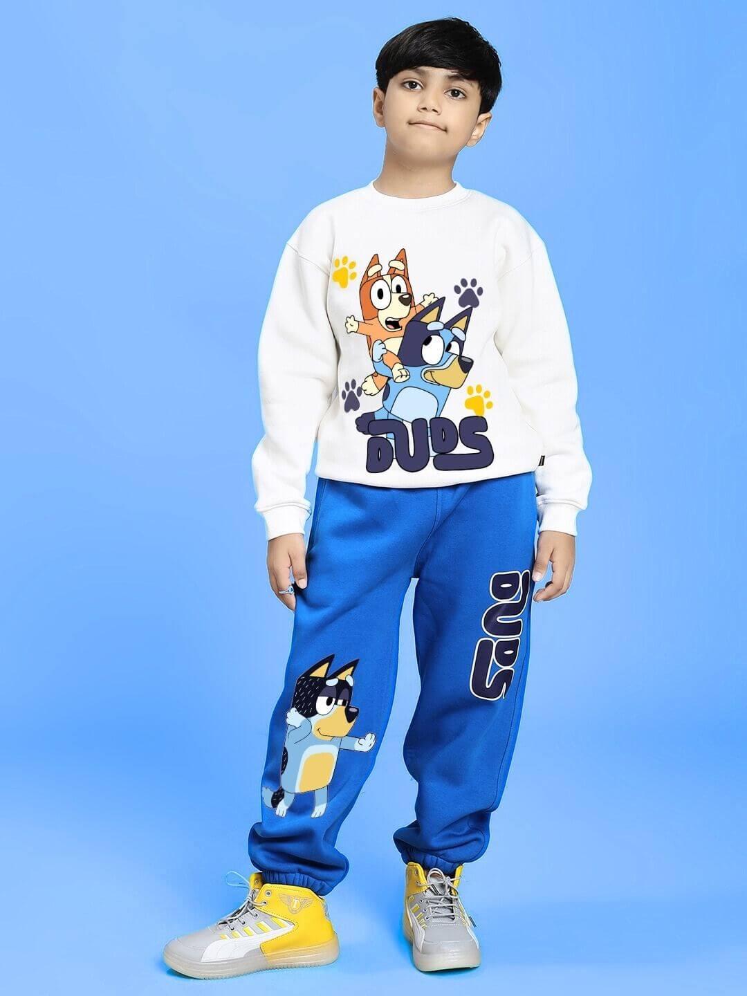 Child wearing BLUEY BINGO FLEECE SWEATSHIRT FOR BOYS AND GIRLS WHITE with cartoon characters, standing against a blue background.