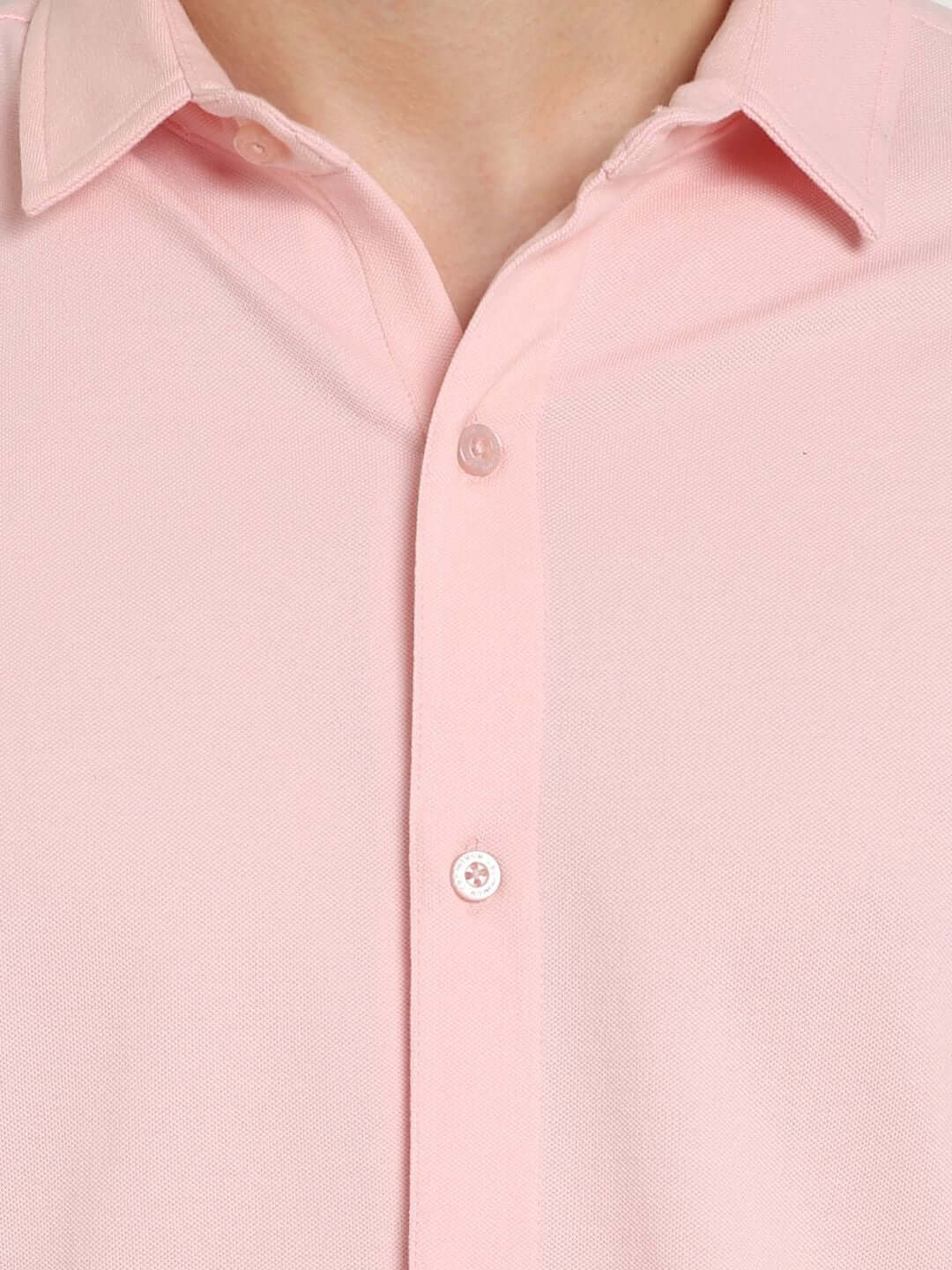 Blush pink sporty pique shirt with full sleeves, wrinkle-free fabric, and a curved hem, showcasing buttons and collar detail.