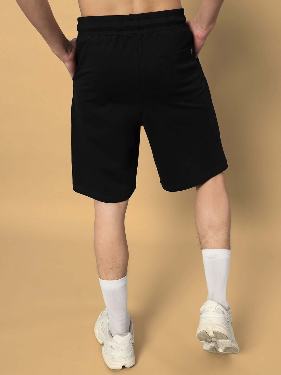 Back view of person wearing black regular fit shorts paired with white socks and sneakers, ideal for showing casual style.