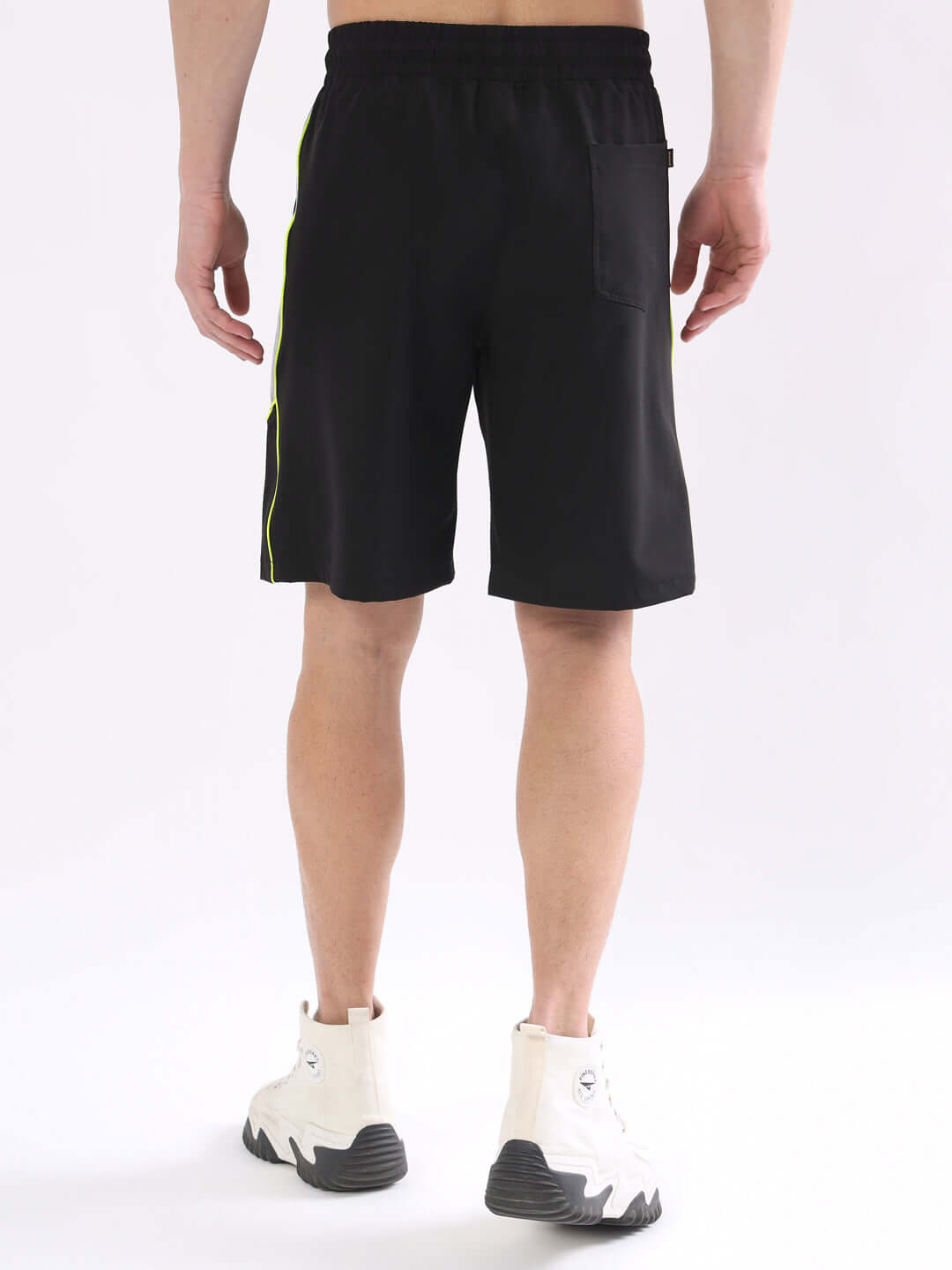 Back view of Boomer shorts in black with neon green piping, offering custom fit, shown worn by model.