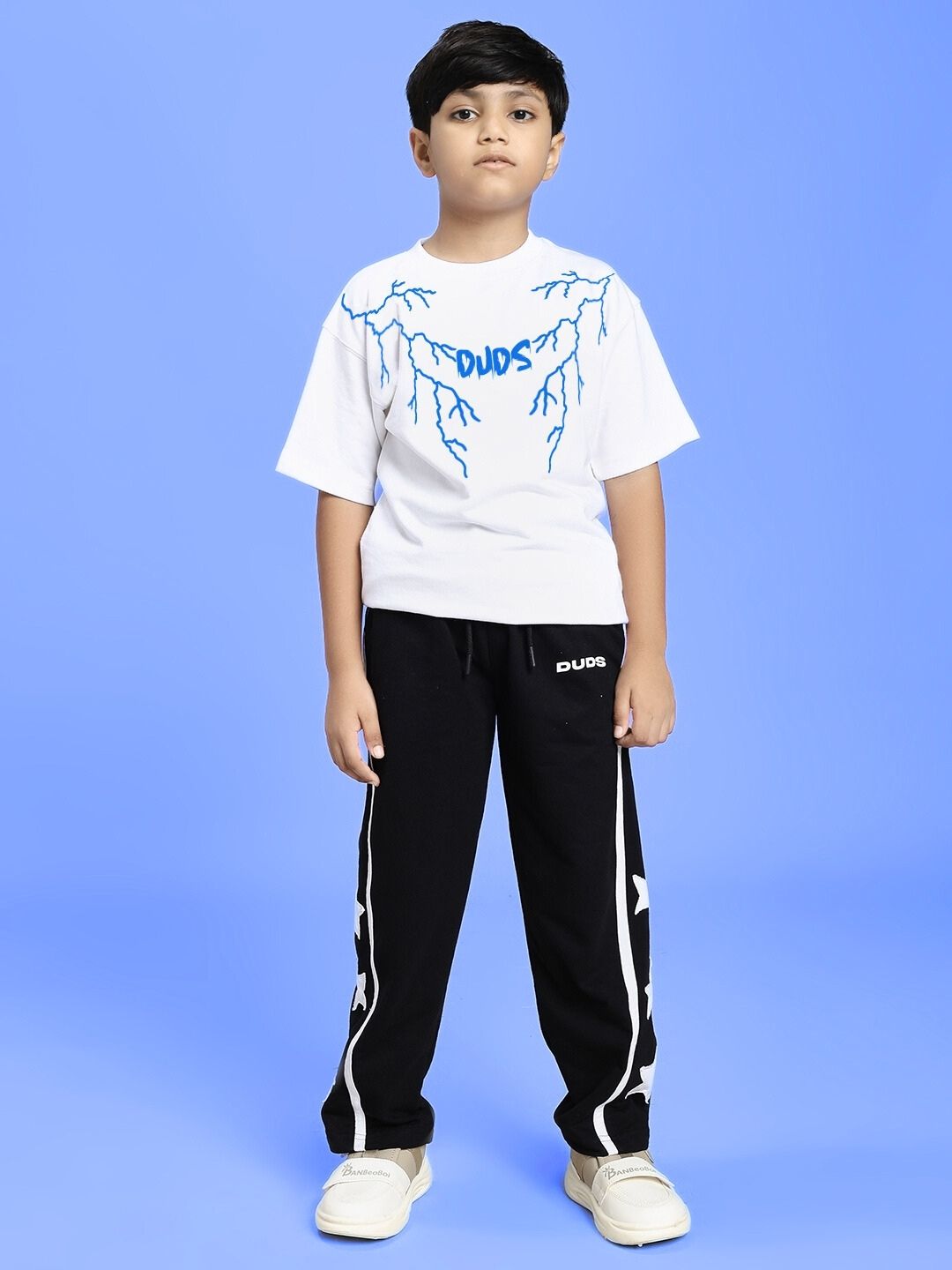 Child wearing a stylish white t-shirt and black pants against a blue background.