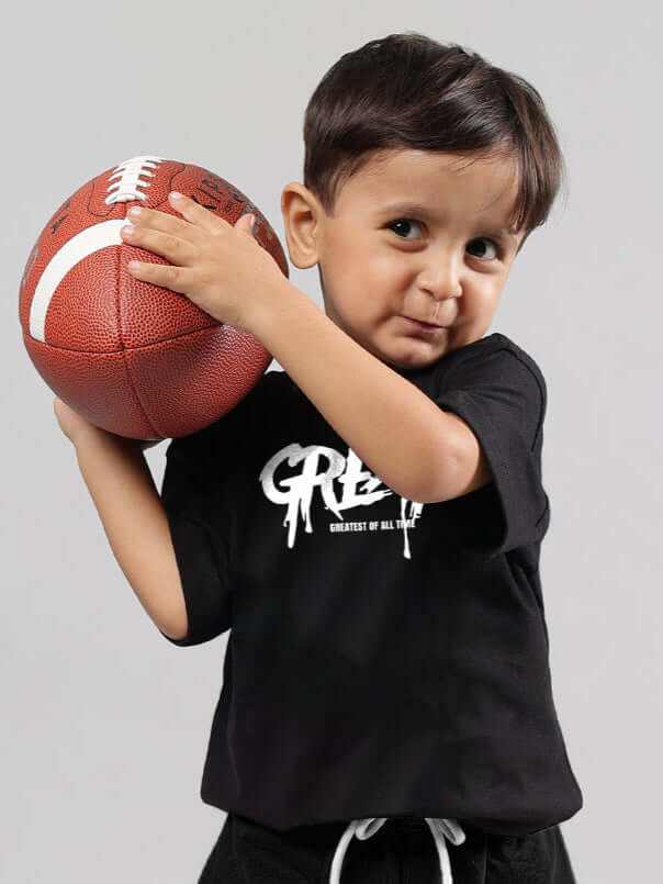 Boy wearing black printed oversized t-shirt holding football, made-to-order from DUDS, available for custom fit, 7-10 days dispatch.