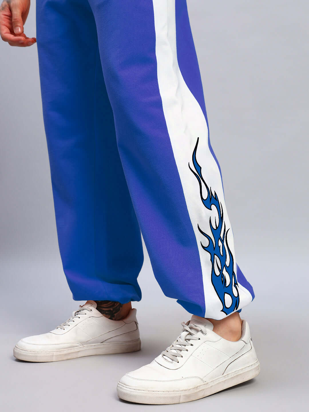 Person wearing BRACER RELAXED FIT JOGGERS BLUE-WHITE with flame design, paired with white sneakers