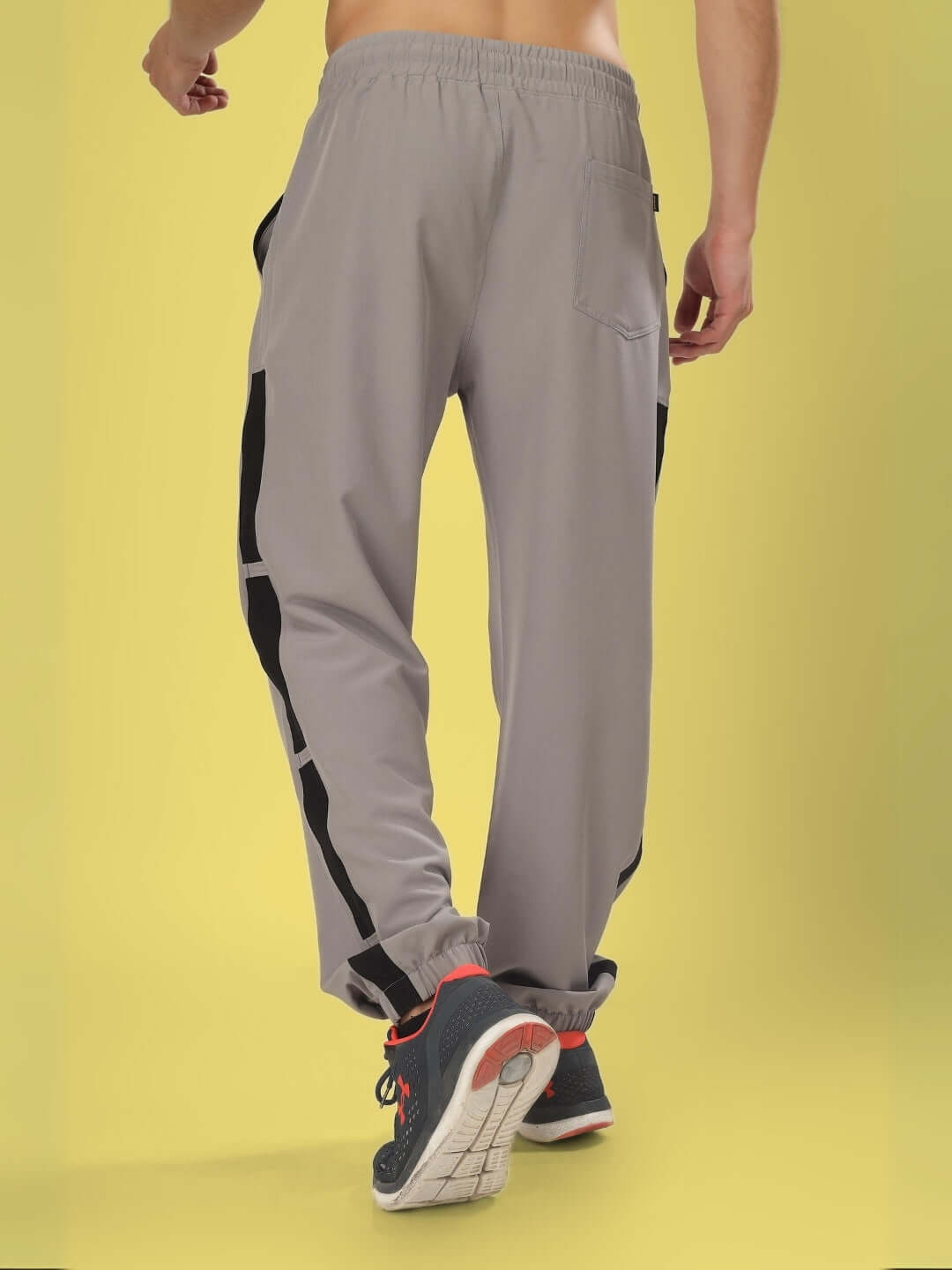 Back view of Bravo Relaxed Fit Cargo Pants in grey with customizable size option, shown on a model against a yellow background.