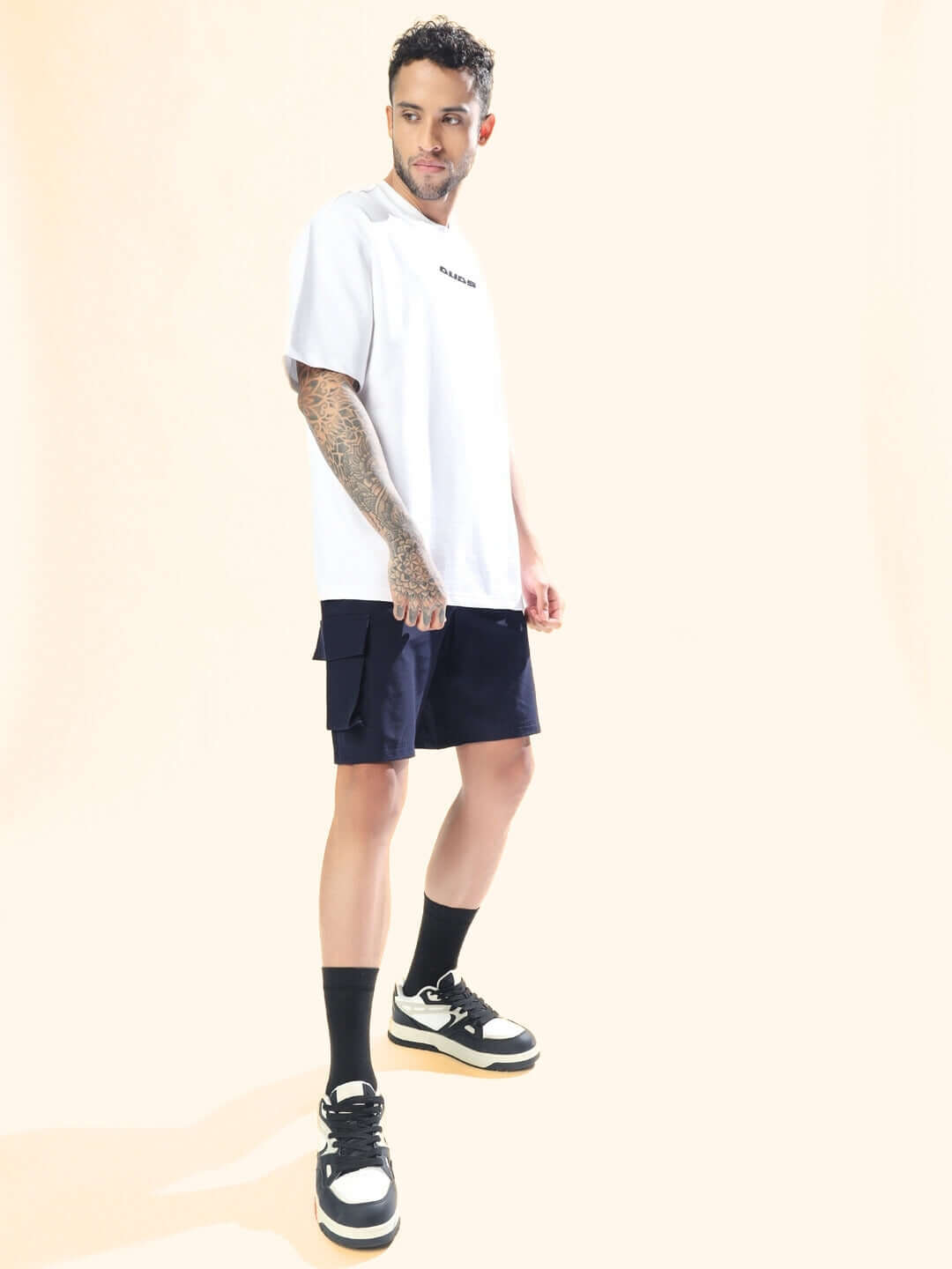 Model wearing navy blue Brawny Cargo Shorts and white t-shirt, standing in a light background.