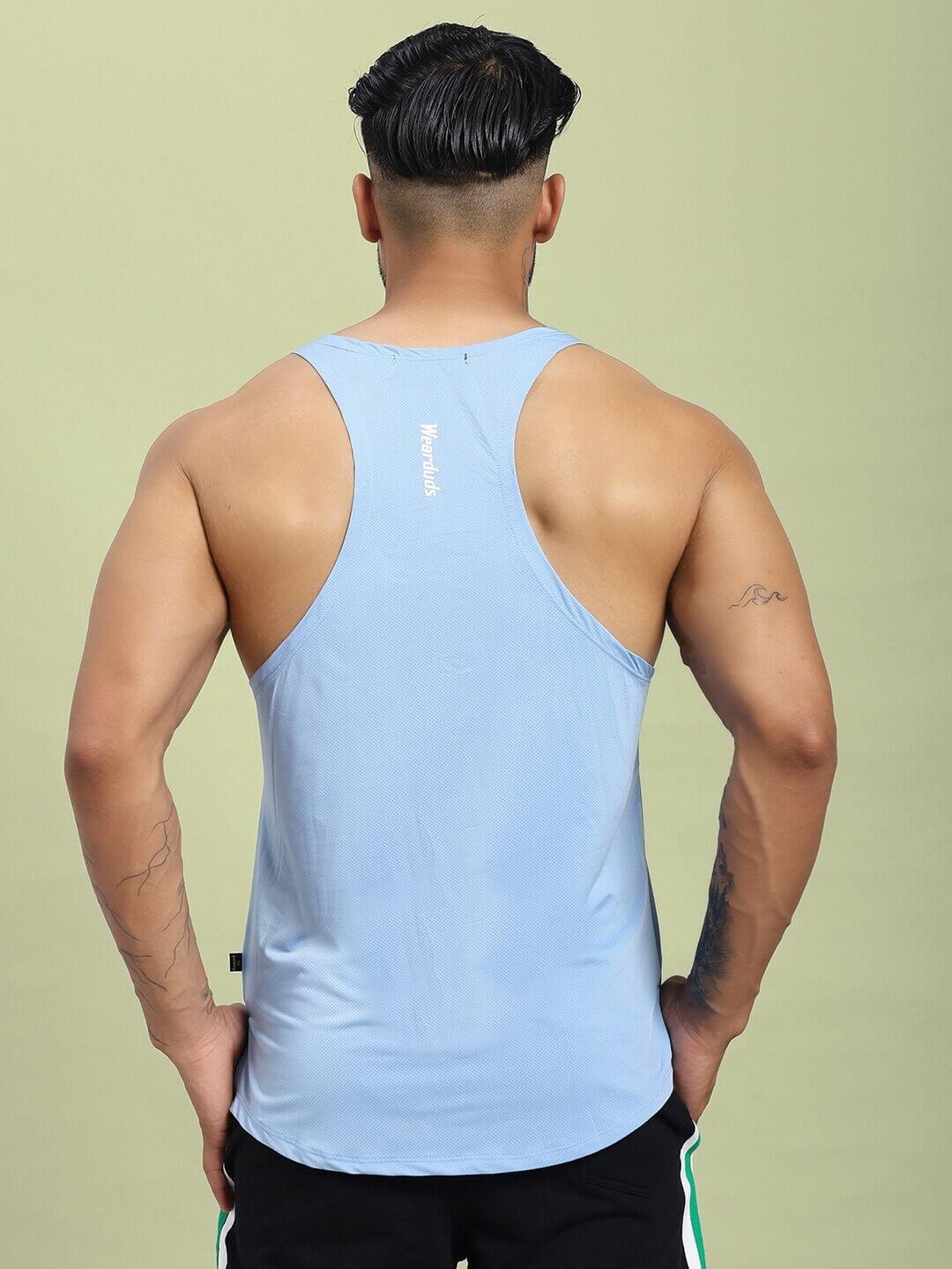 Back view of a man wearing a BREEZE COMFORT GYM T-SHIRT LIGHT BLUE with a racerback design, showcasing the light blue color and fit.