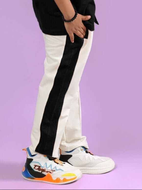 Child wearing Breezer Jogger in off white and black, standing on a purple background, showcasing stylish colorful sneakers.