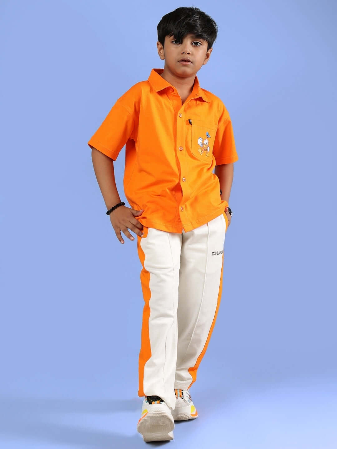 Child wearing an orange and off-white Breezer Jogger by DUDS, tailored for boys and girls, made with premium craftsmanship.