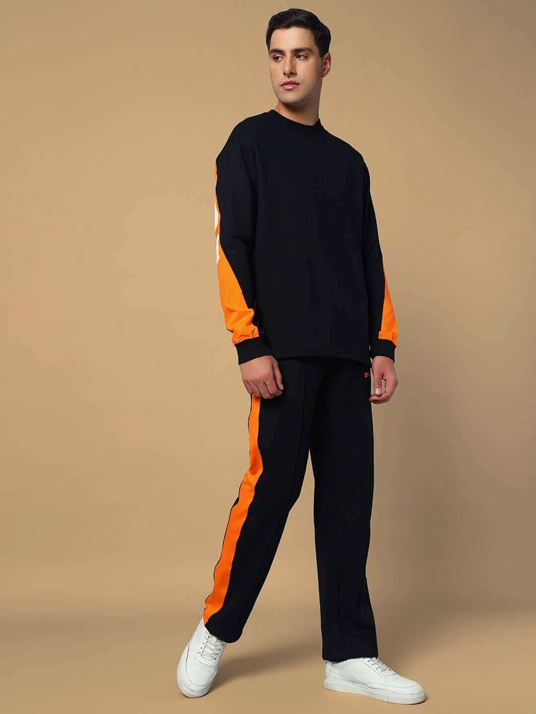 Model wearing black joggers with orange side contrast, styled with a matching sweater, showcasing Breezer side joggers by DUDS.