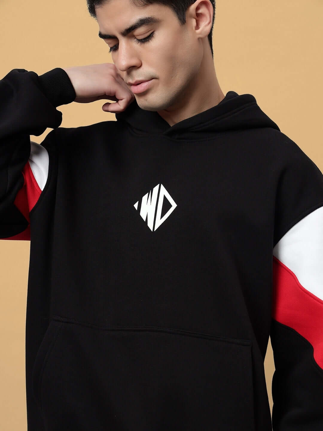 Stylish black fleece colorblock hoodie featuring red and white accents, worn by a model against a beige background.