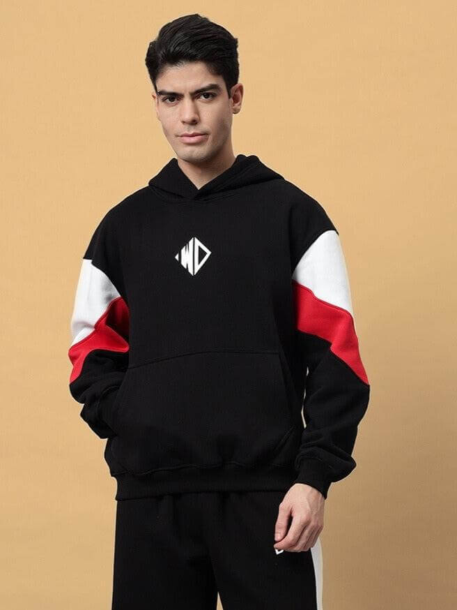 Man wearing a black BRIO fleece colorblock hoodie with red and white accents, featuring a front pocket and hood.