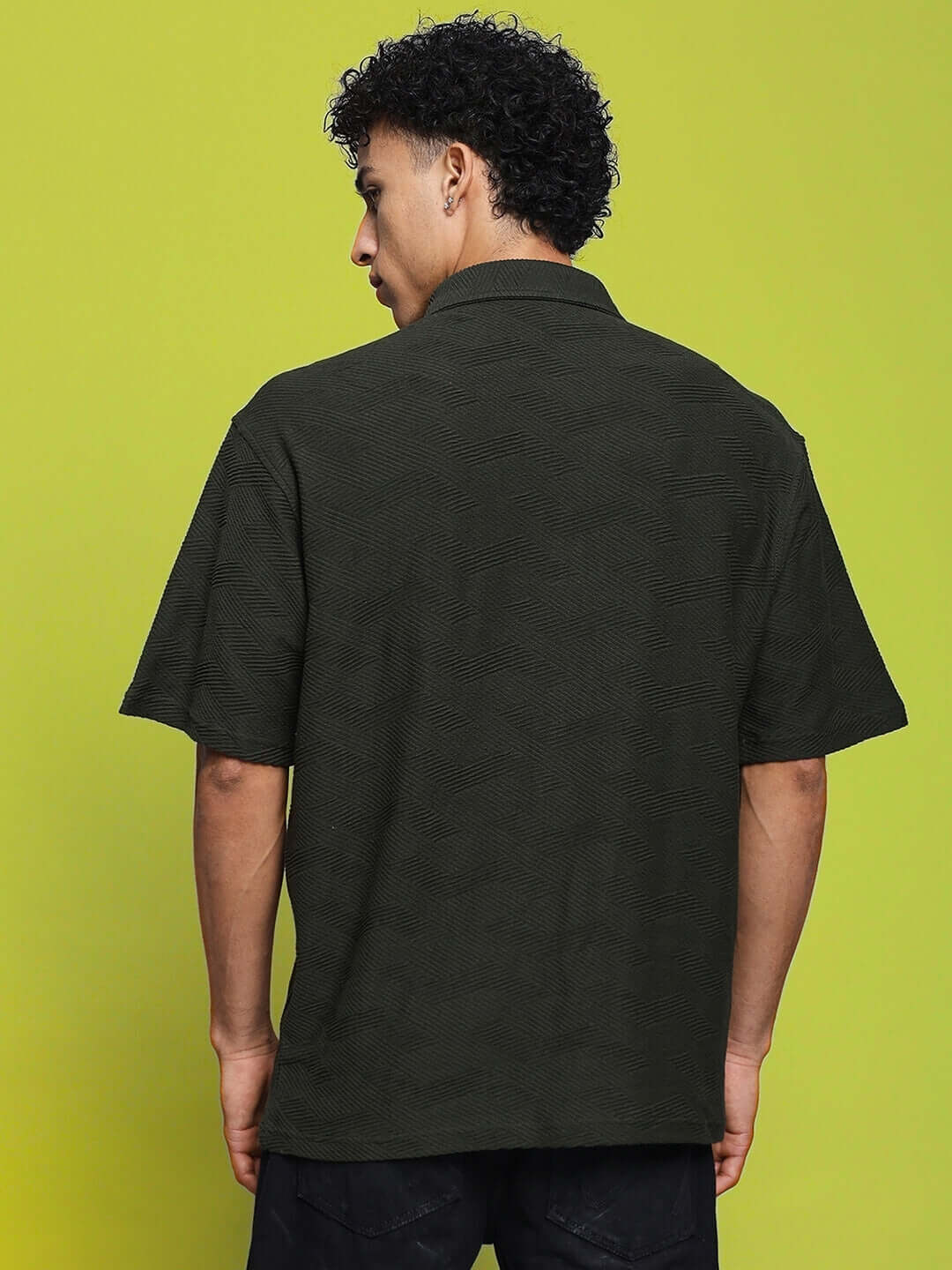 Back view of model wearing BROCADE POLO T-SHIRT DARK GREEN against a green background.