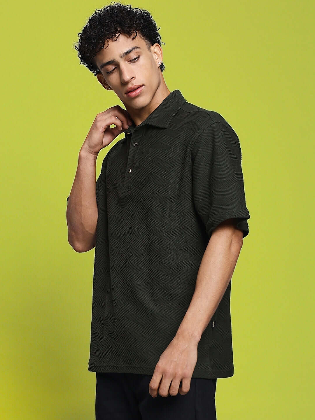 Man wearing BROCADE POLO T-SHIRT DARK GREEN, showcasing textured jacquard-style fabric on yellow background