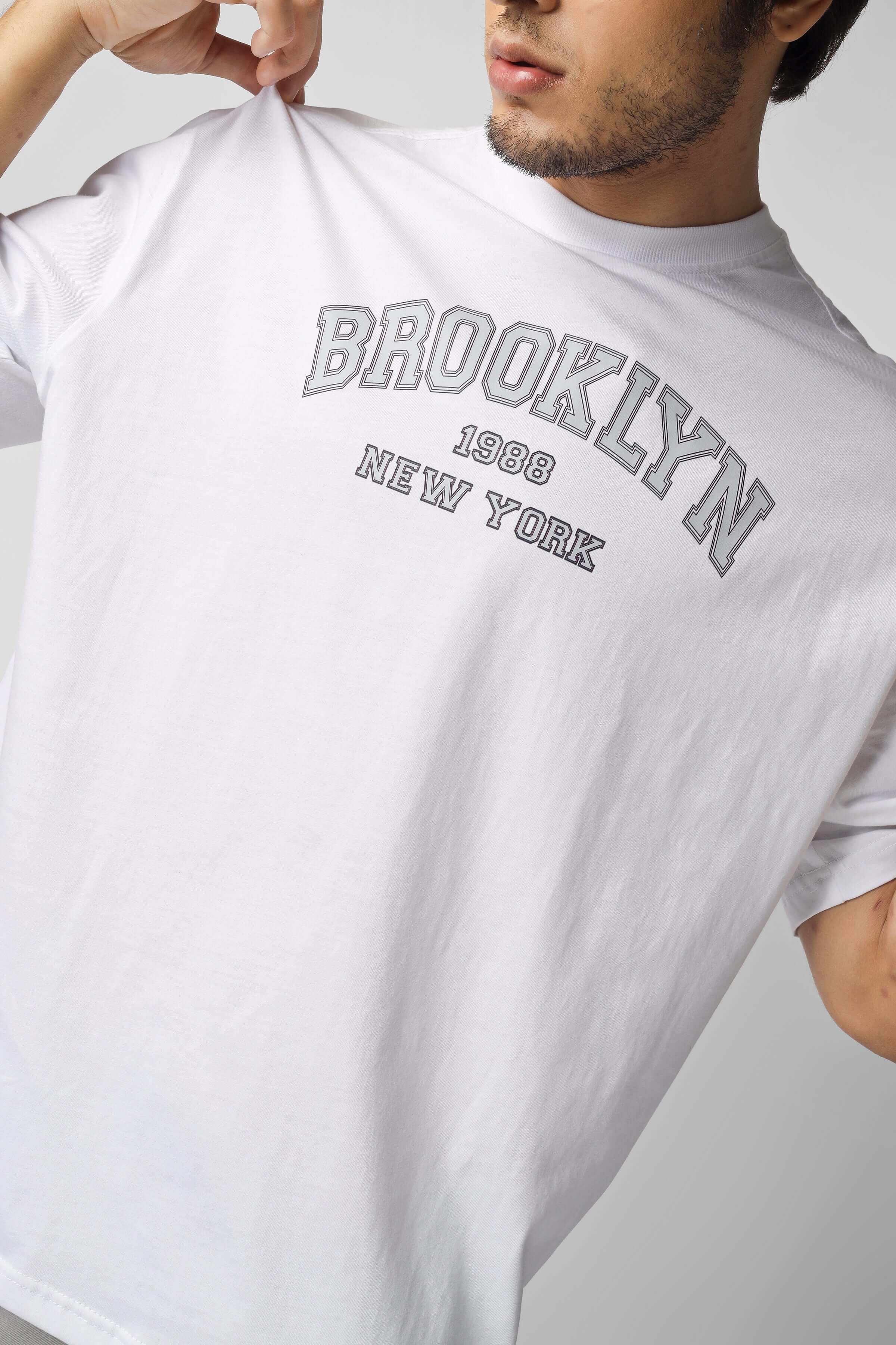 Person wearing Brooklyn New York t-shirt in white, showcasing bold text design.
